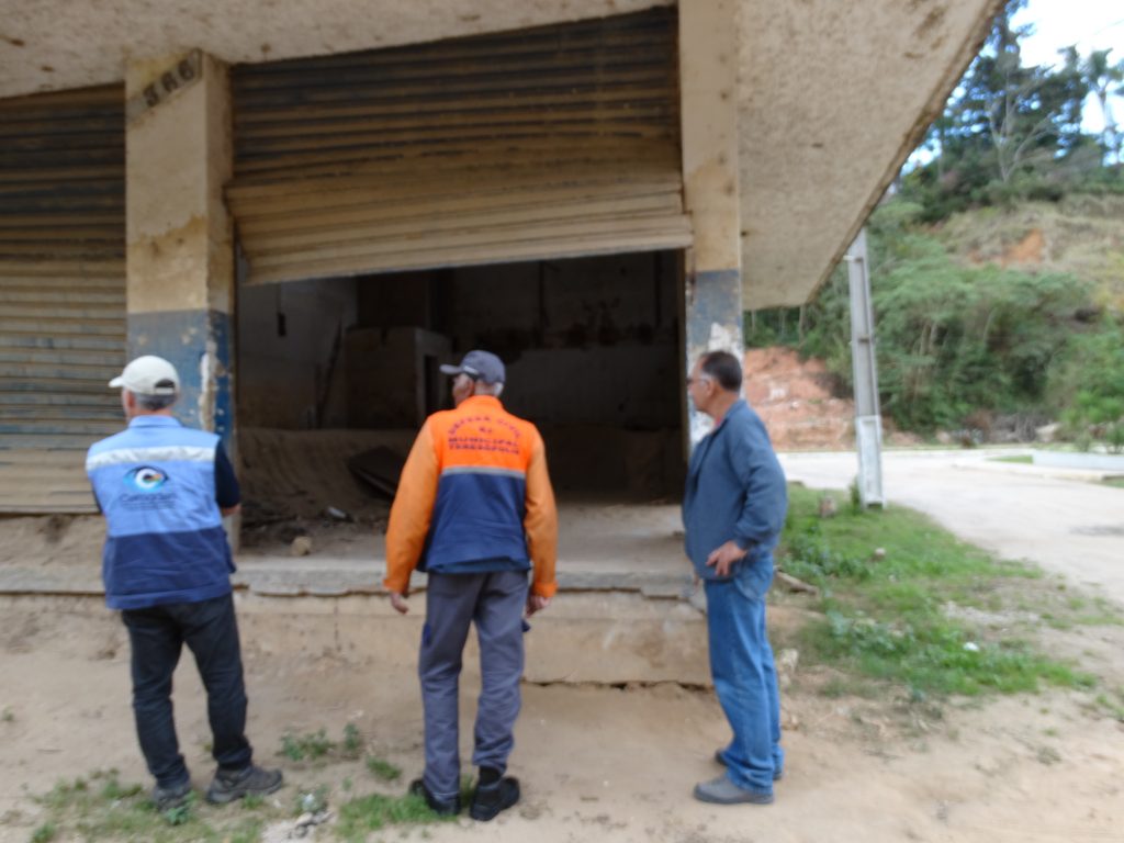 Moradores que vivenciaram o desastre de 2011, em Teresópolis (RJ), junto a geólogo do Cemaden, observam o nível de terra depositado no comércio, resultado da inundação com detritos do Rio Paquequer. 
